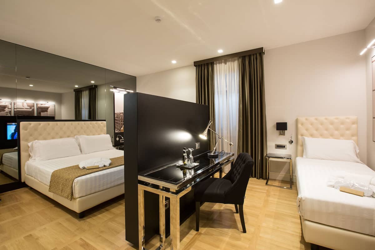 A hotel room with two beds, a desk, a chair, a TV, and a mirror.