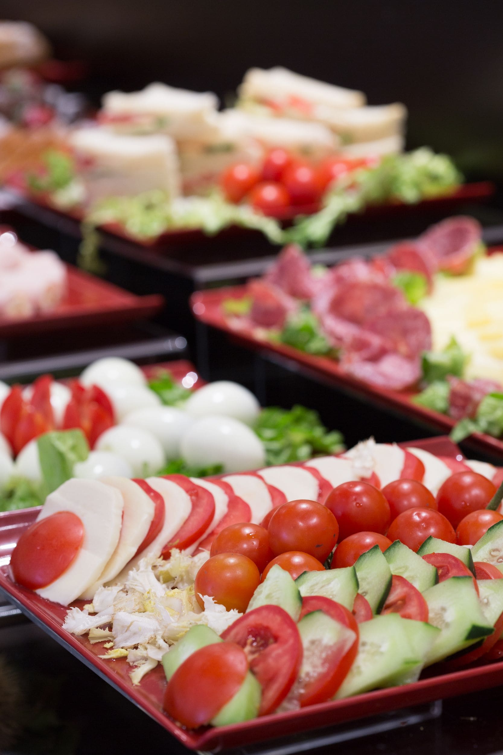 A buffet with various food items including sliced tomatoes, cucumbers, and cheese.
