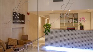 Ein Hotel-Empfangsbereich mit modernem Design, inklusive einer Rezeption, einer Sitzecke und einer großen Pflanze in einem Topf.