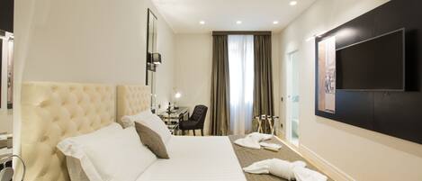 A hotel room with a large bed, a desk, a chair, and a television on the wall.