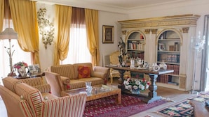 A traditional living room with striped sofas, a coffee table, a bookshelf, and a floral rug. - B&B Triskéles (Agrigento)