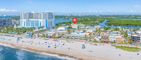 A coastal cityscape with a beachfront, high-rise hotels, and a marina.
