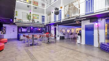 Un espacio interior de varios niveles con una zona de bar, asientos y un suelo a cuadros.