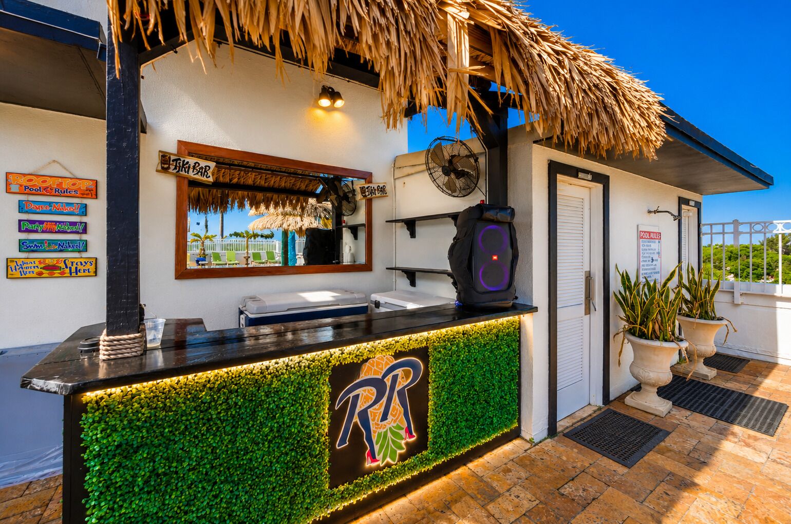 A tiki bar with a thatched roof, a pool table, and a sign indicating pool rules.