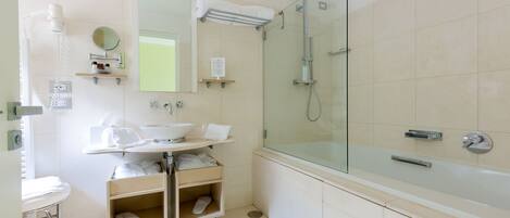 A modern bathroom with a glass-enclosed shower, a sink with a mirror, and a storage cart with toiletries.