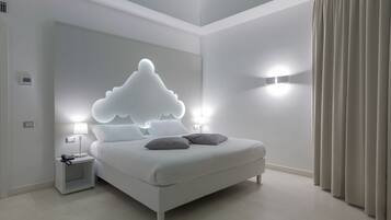 Un dormitori modern amb un llit, tauletes de nit i una lluminària de disseny amb forma de núvol.