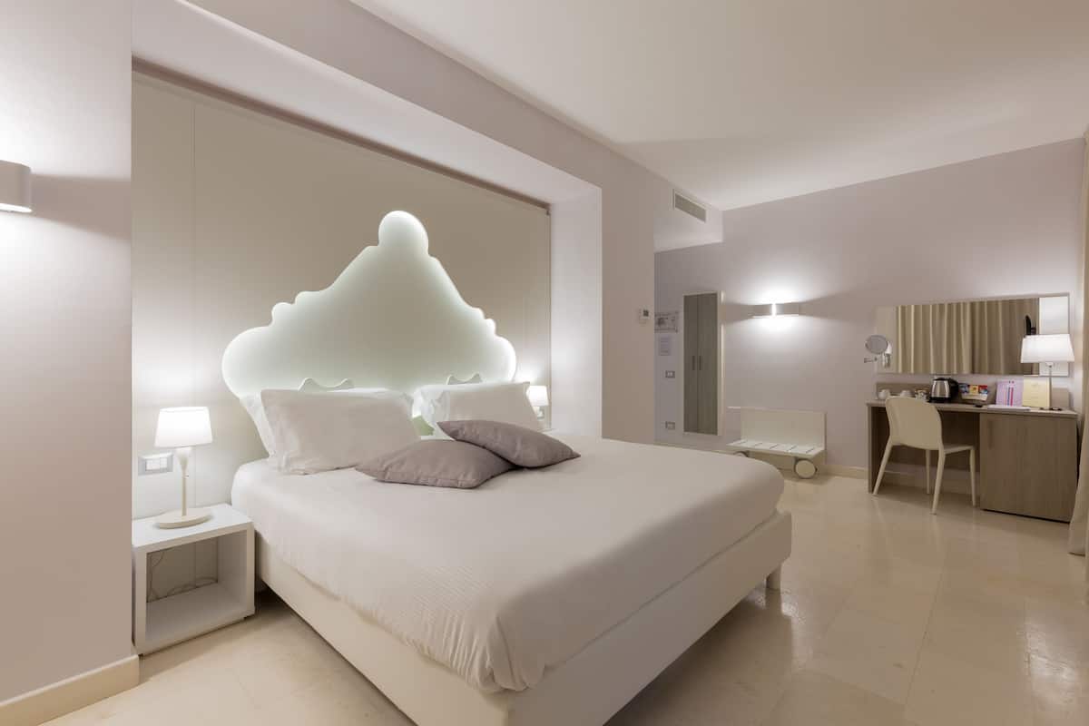 A modern hotel room with a large bed, bedside tables, a desk, and a chair.