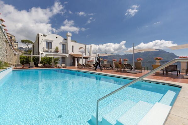 Alberca al aire libre, sombrillas en la alberca y camastros 