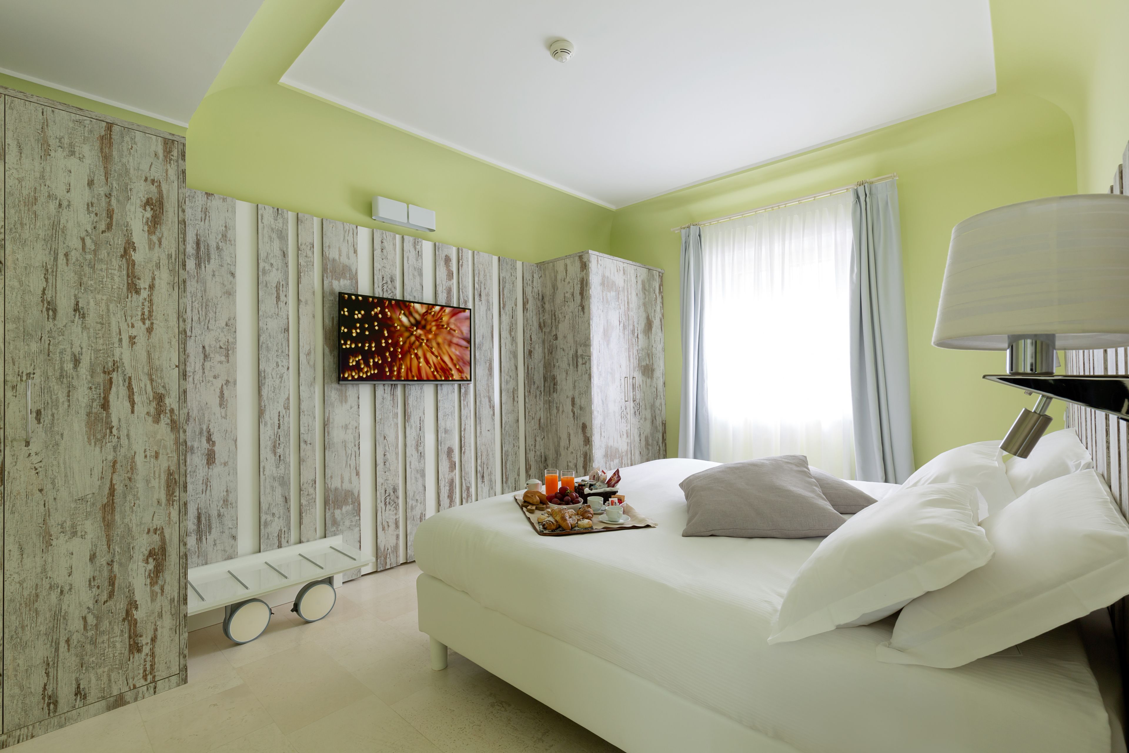 A modern bedroom with a bed, a flat-screen TV, and a breakfast tray.