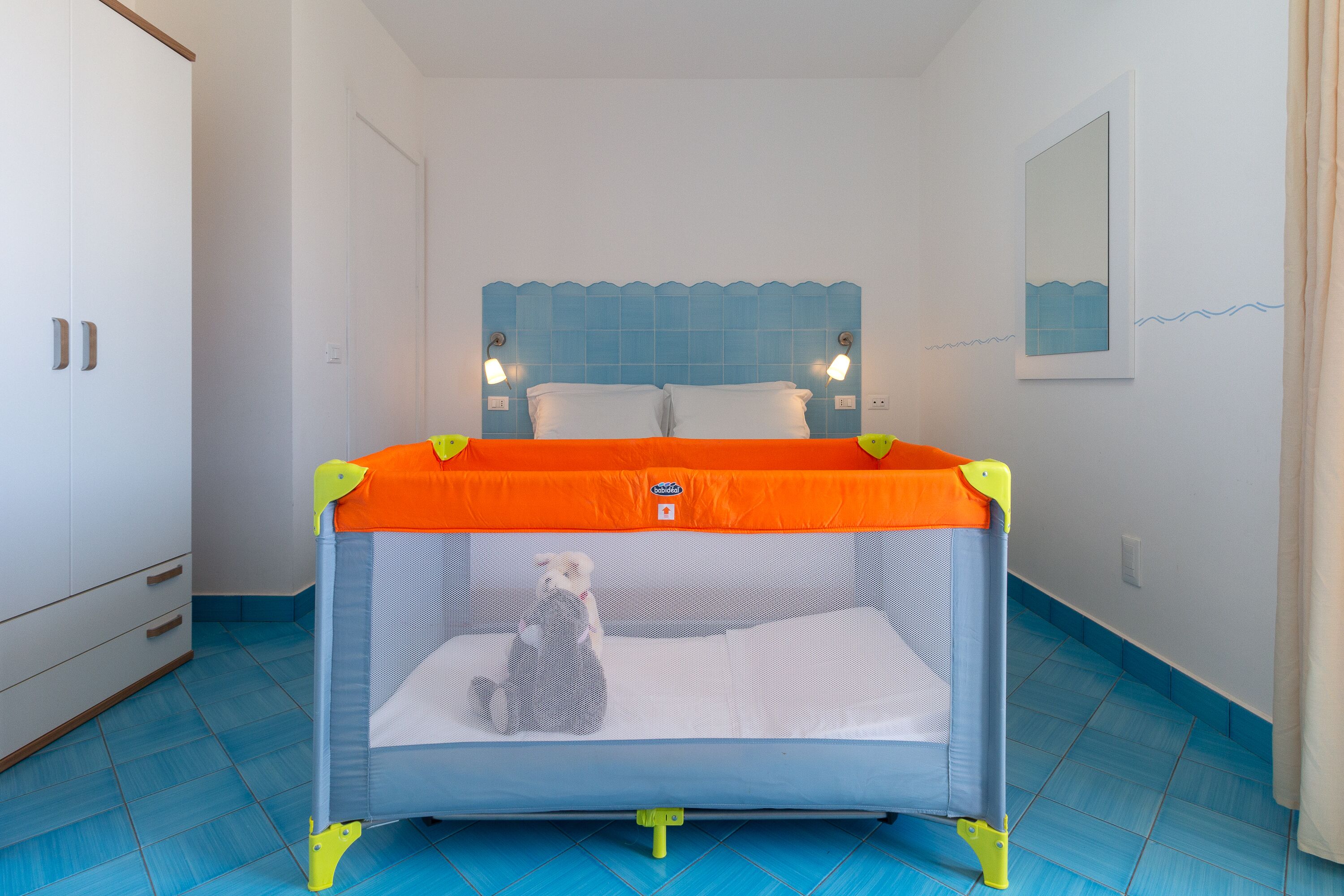A room with a bed, a wardrobe, and a bathroom with a mirror.