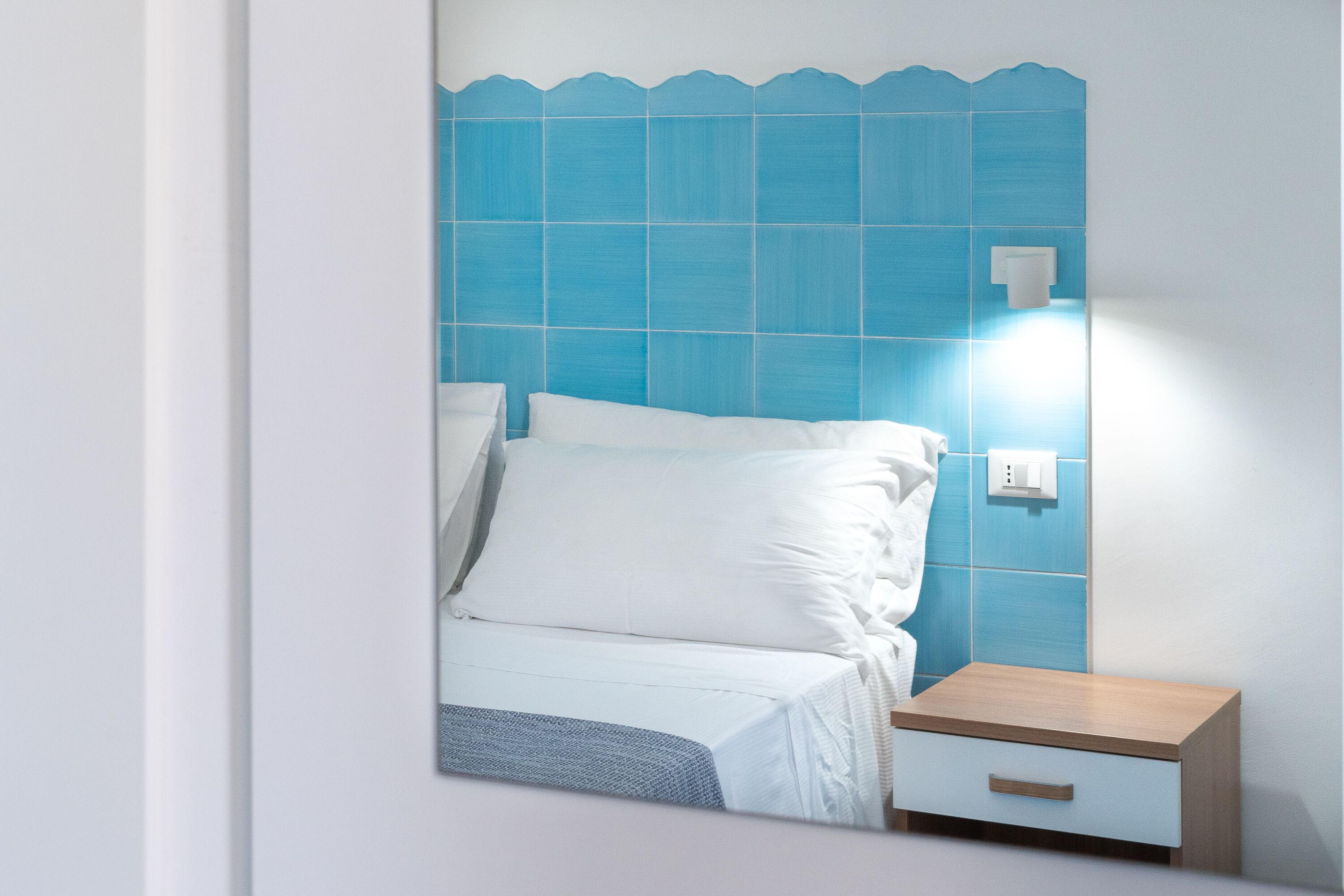Um quarto com uma cama, uma mesa de cabeceira e uma luminária na parede.