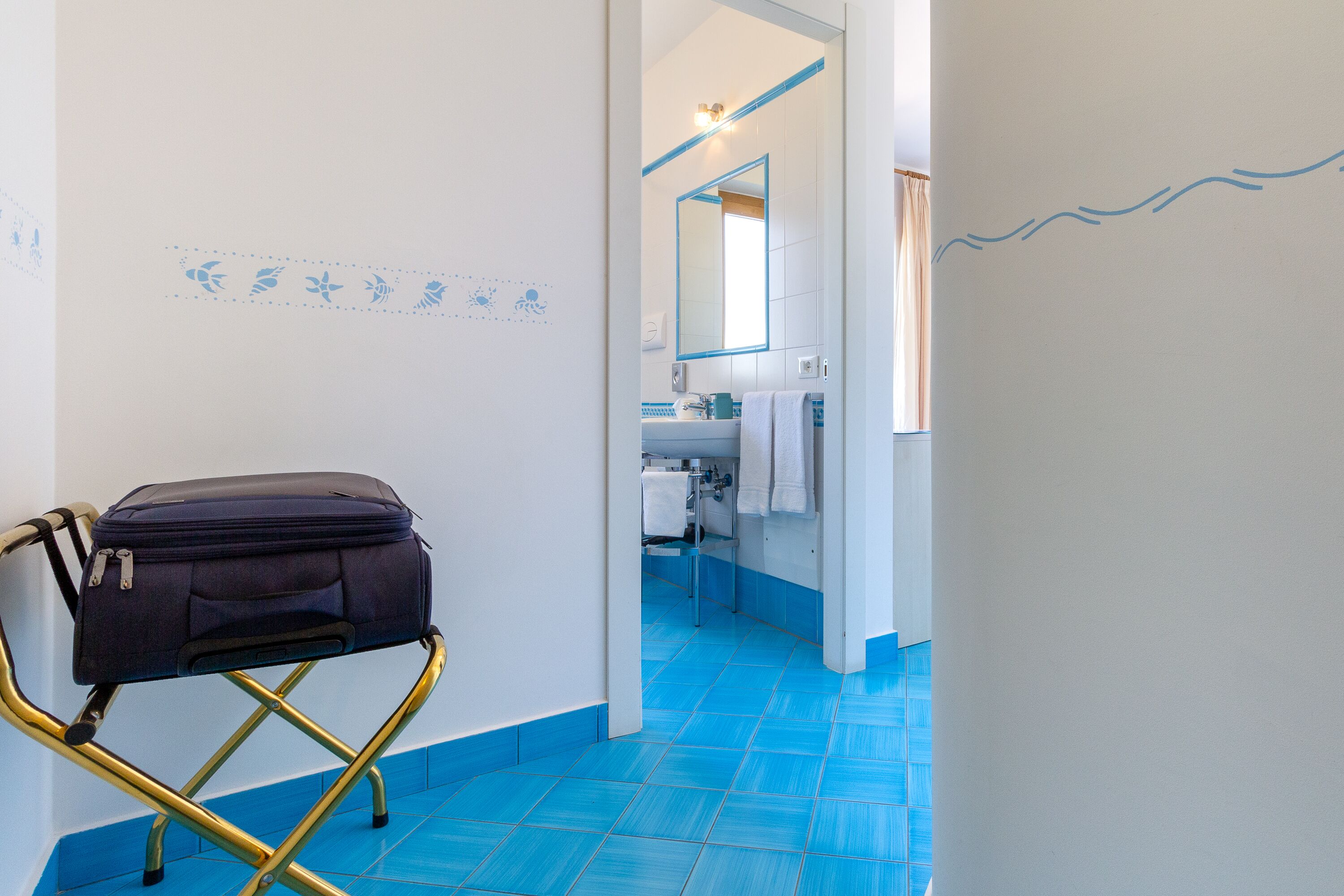 Een badkamer met een blauwe betegelde vloer, een witte wastafel en een spiegel.