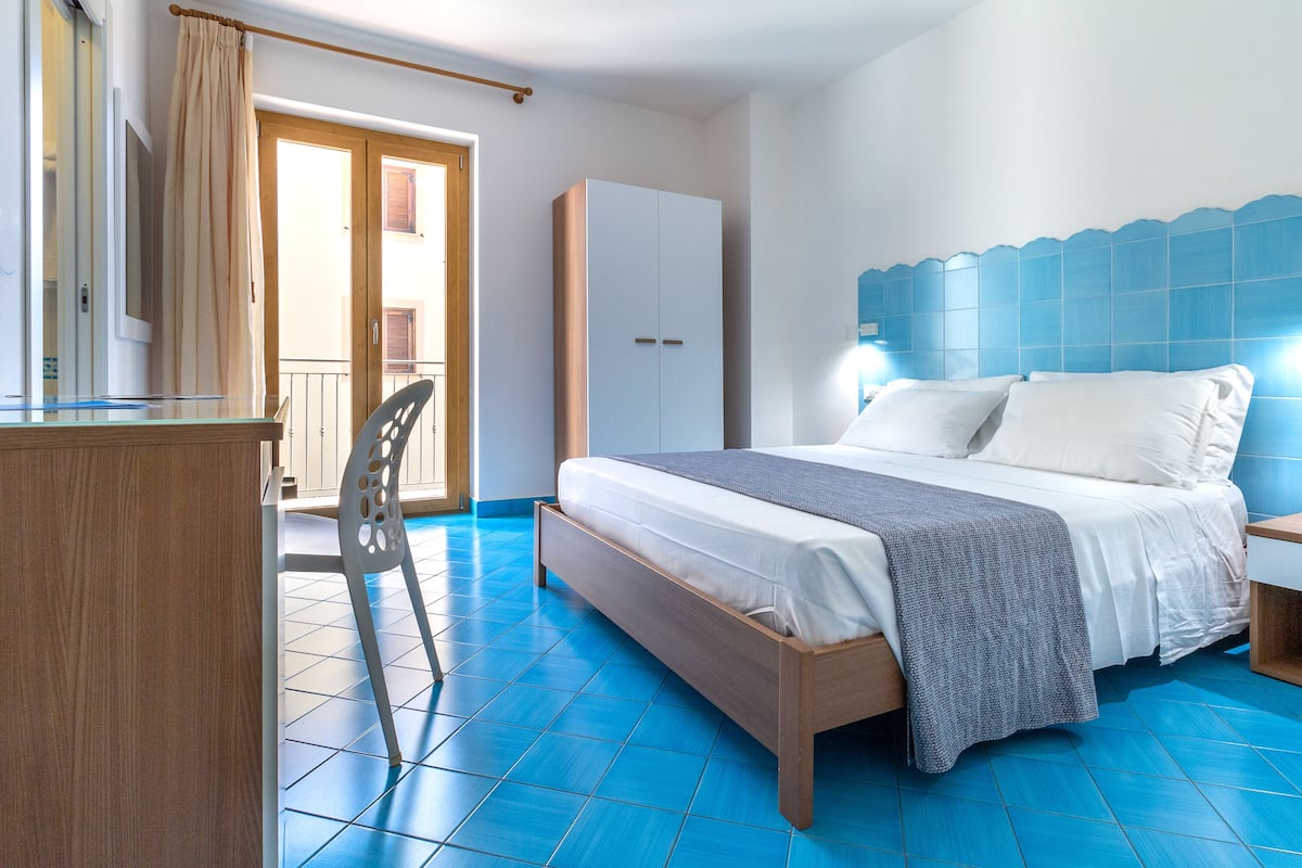 Ein Schlafzimmer mit einem Bett, einem Kleiderschrank, einem Schreibtisch und einem Stuhl.