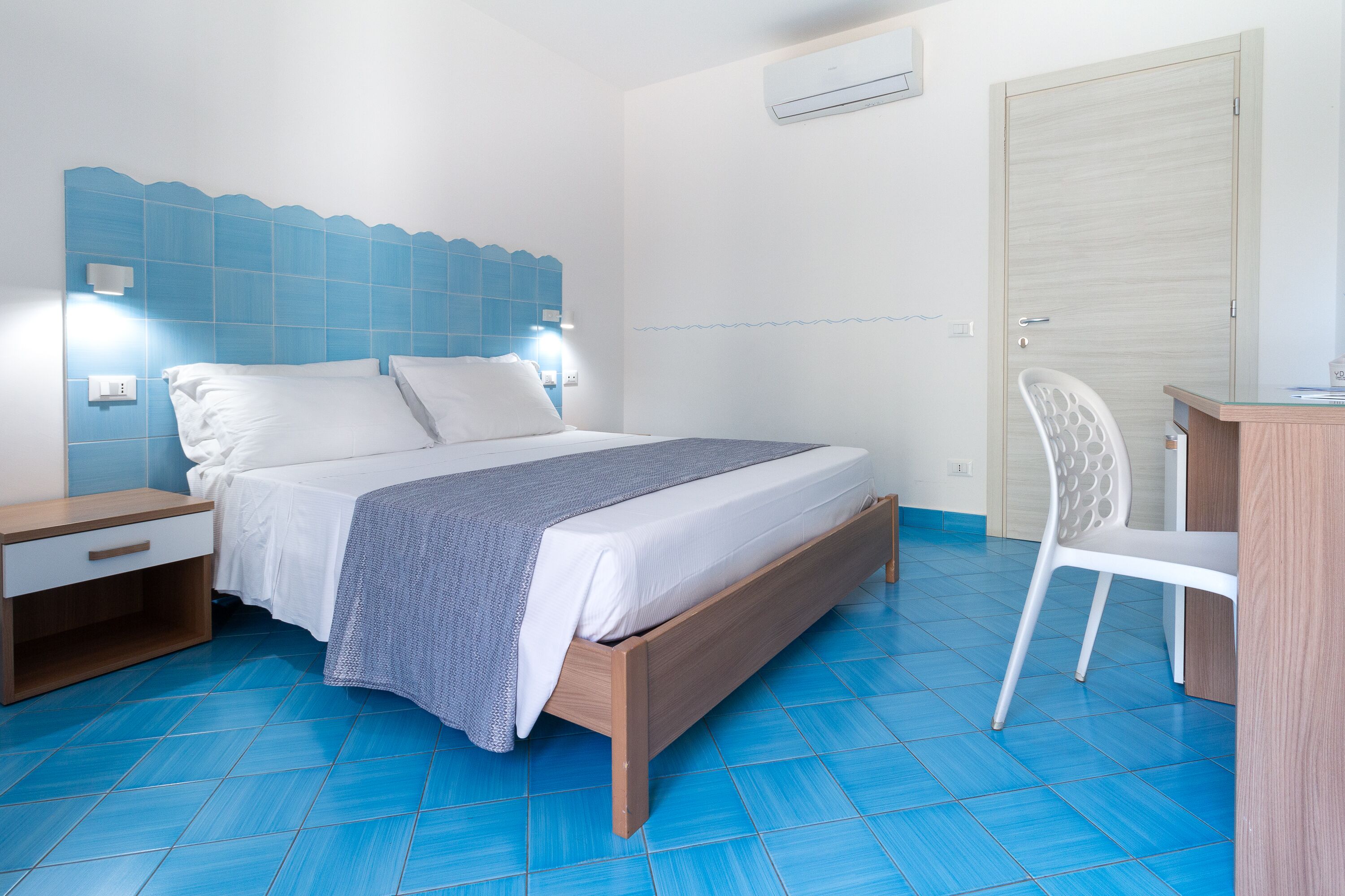 Un dormitorio con cama, mesita de noche, silla y escritorio.