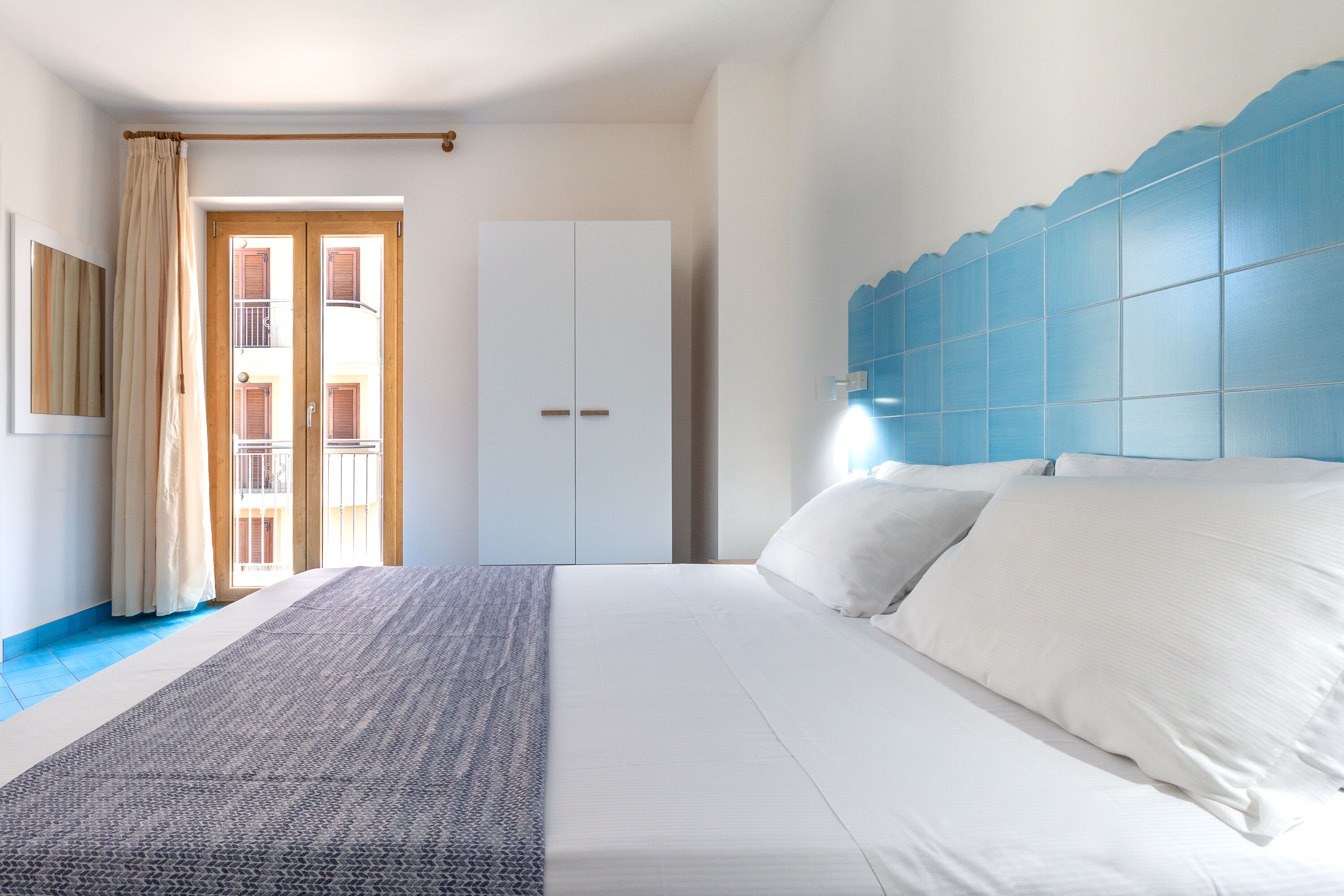 A bedroom with a bed, a wardrobe, and a view of the outside balcony.