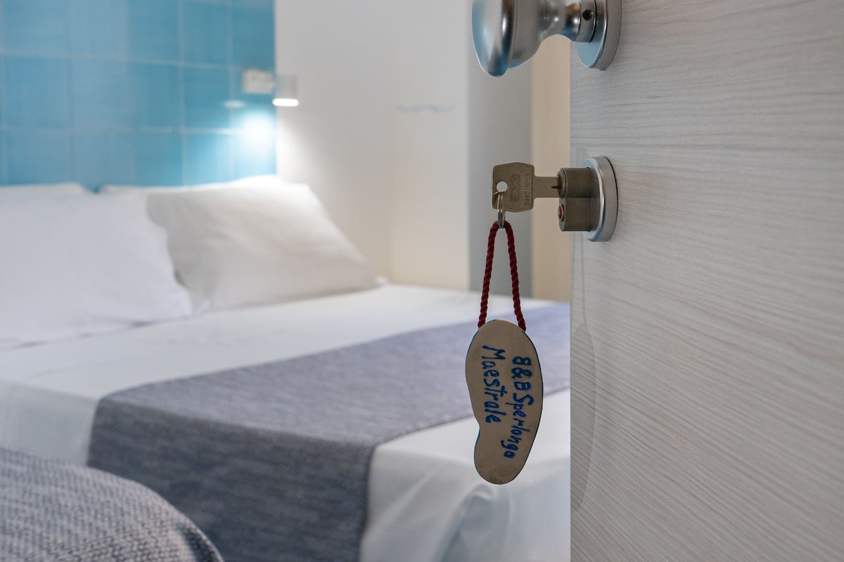 Ein Hotelzimmer mit einem Bett, einem Nachttisch und einer Tür mit Schlüsselanhänger.