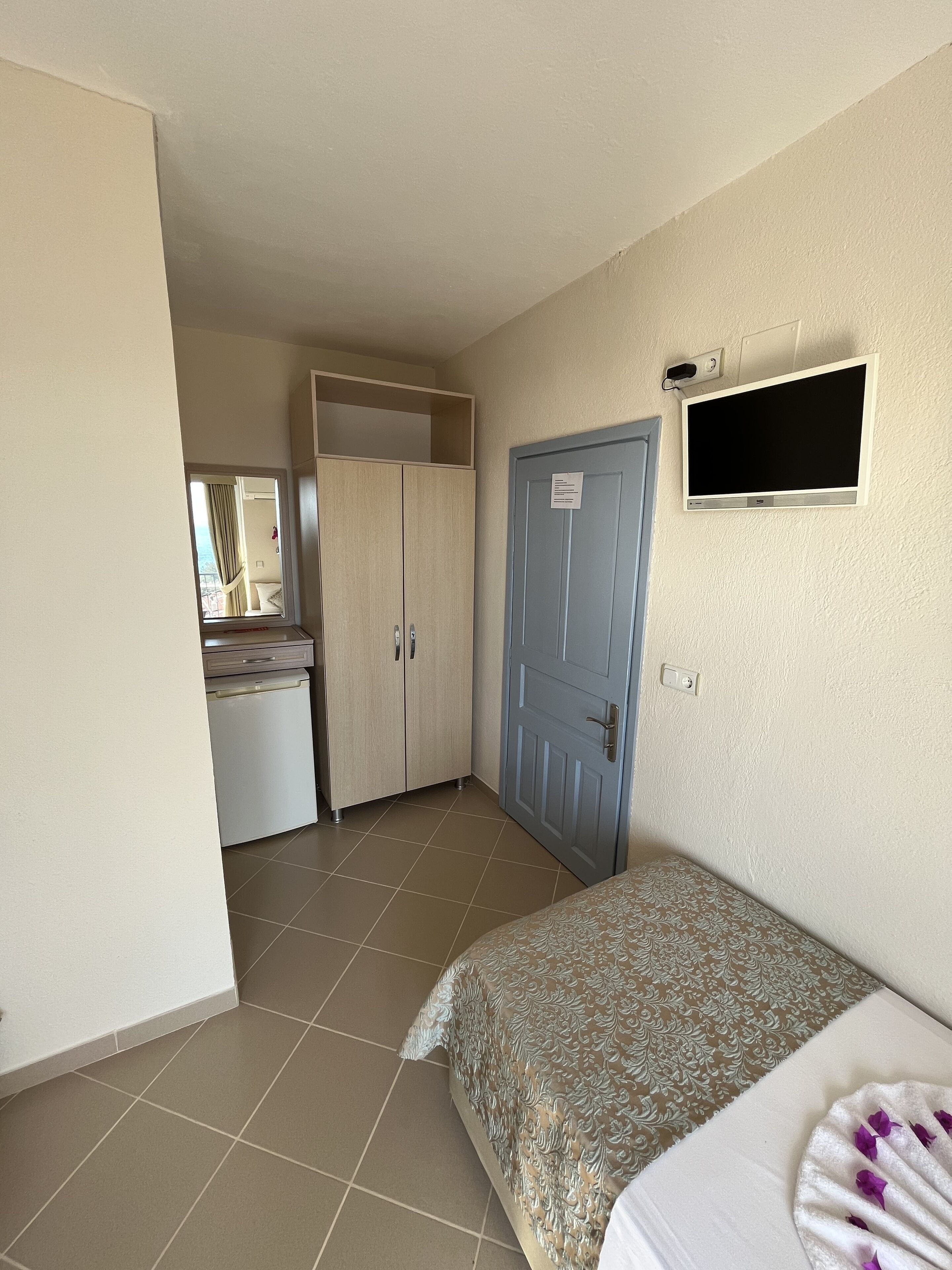 A bedroom with a bed, a wardrobe, a television, and a bathroom visible through an open door.