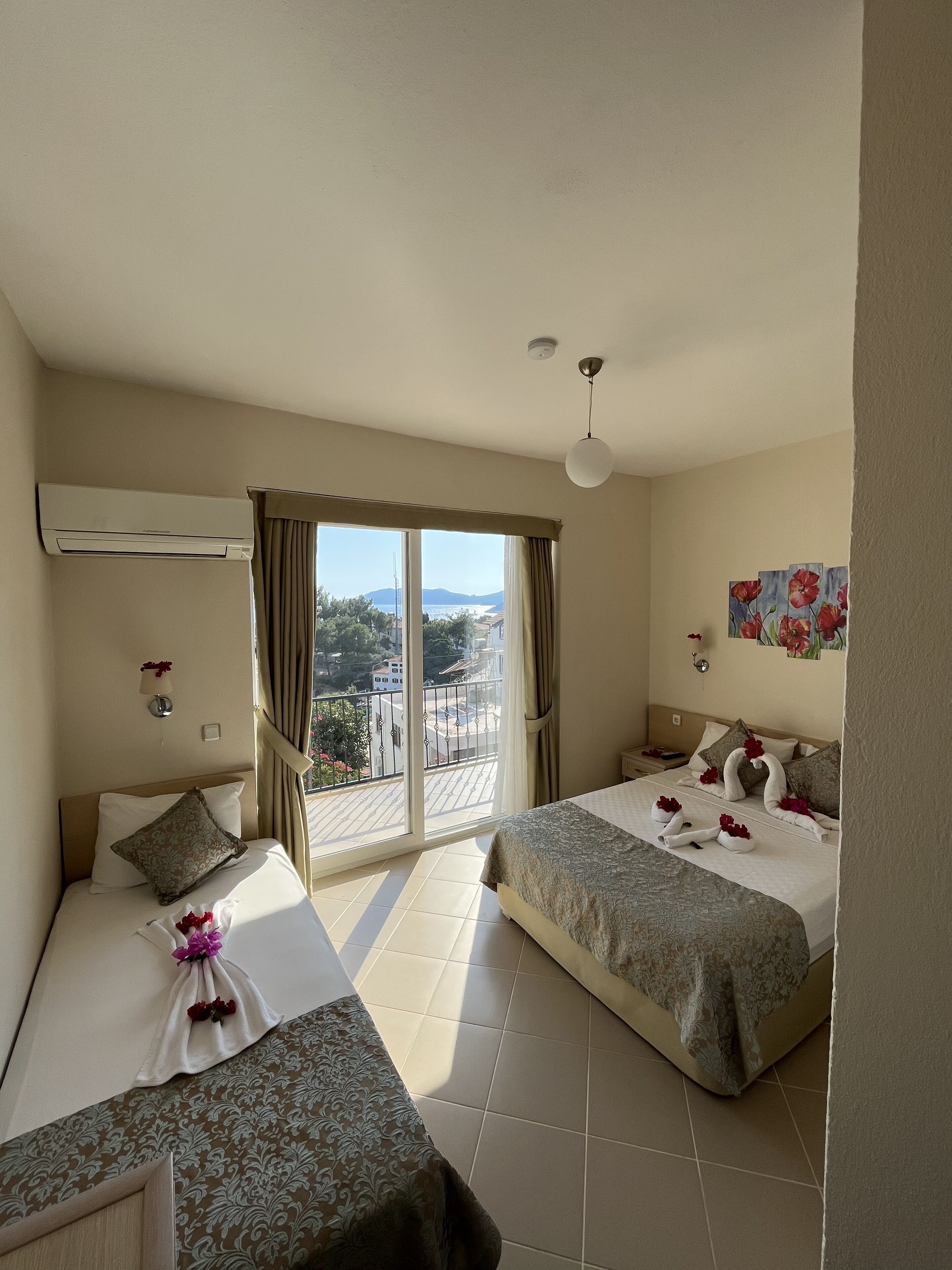 Habitación de hotel con dos camas, un balcón con vistas y un cuadro en la pared.