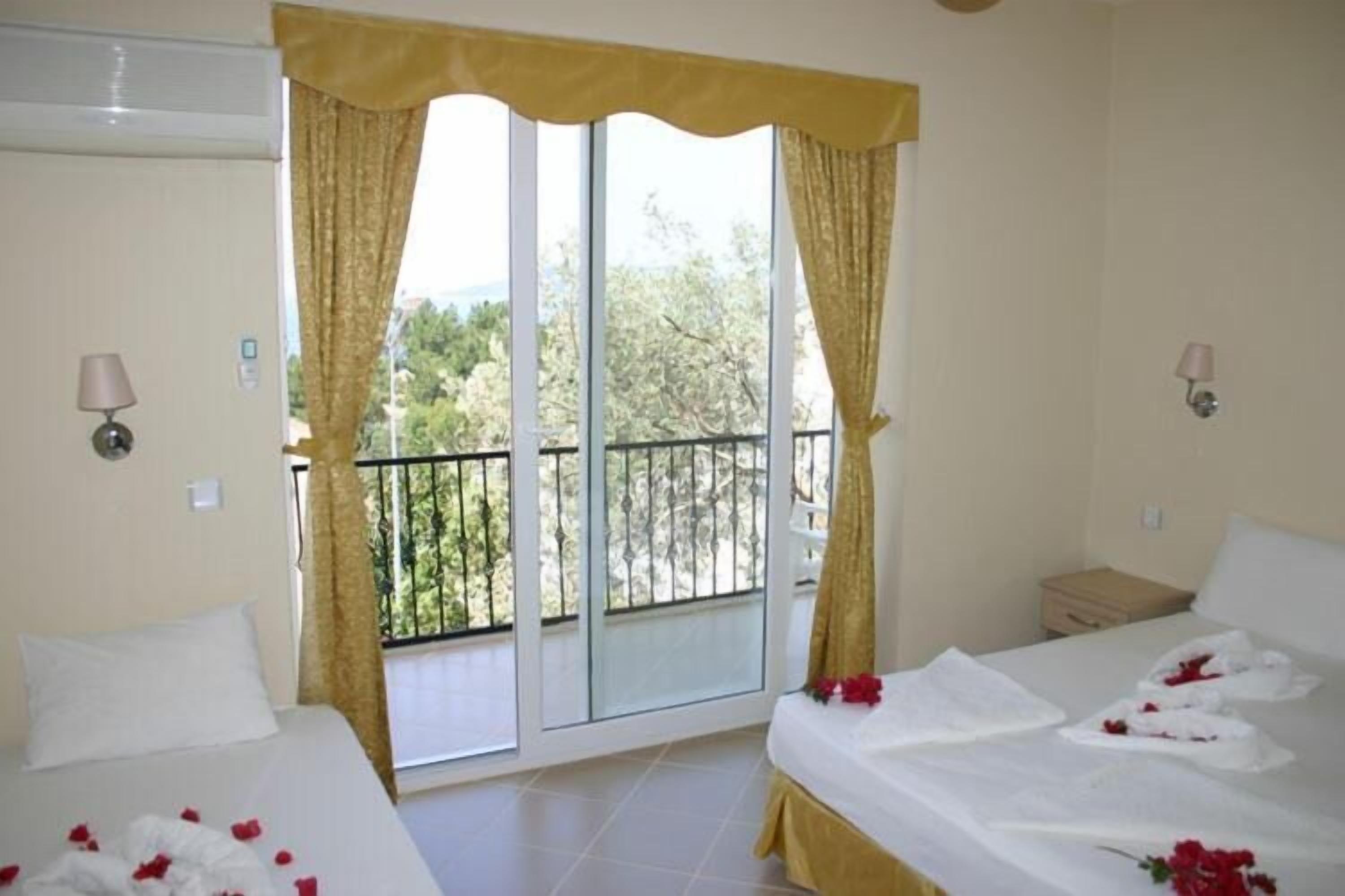 A hotel room with two beds, a balcony with a view, and a sliding glass door.