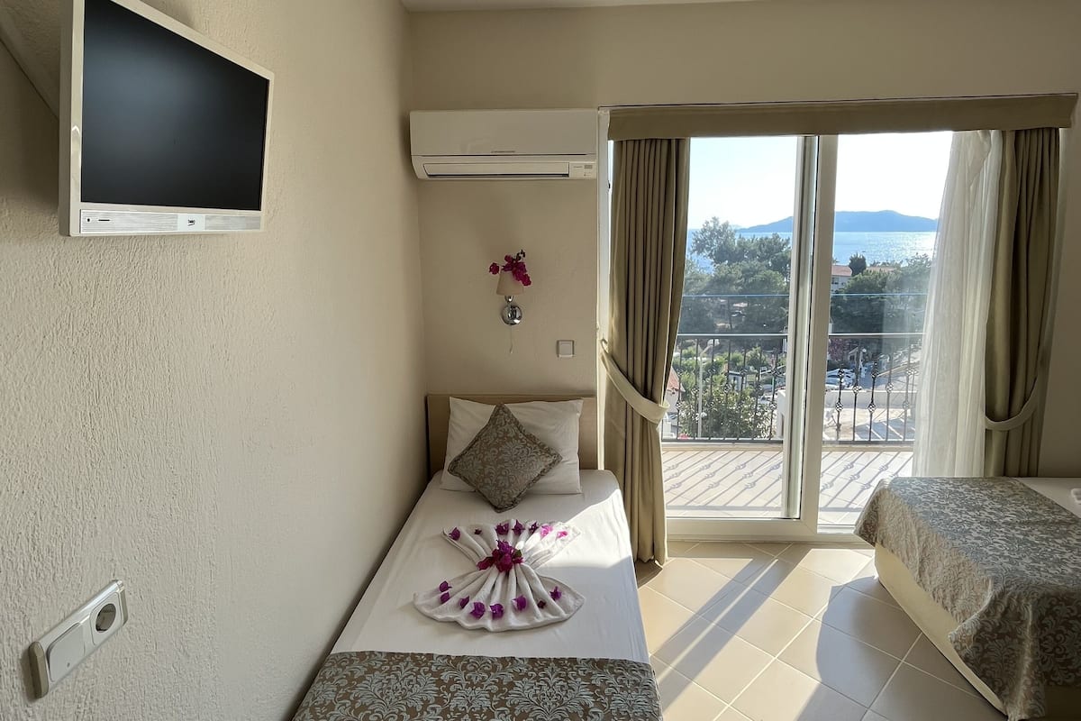 Une chambre d’hôtel équipée d’un lit, d’une télévision, d’un climatiseur, d’une fenêtre avec des rideaux et offrant une vue sur l’extérieur.