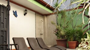 A patio with two lounge chairs, a wall-mounted light fixture, and potted plants. - Hotel La Guaria Inn & Suites (Alajuela)