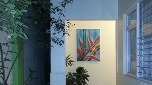 A corridor with a tiled floor, a potted plant, and a painting on the wall. - Hotel La Guaria Inn & Suites (Alajuela)