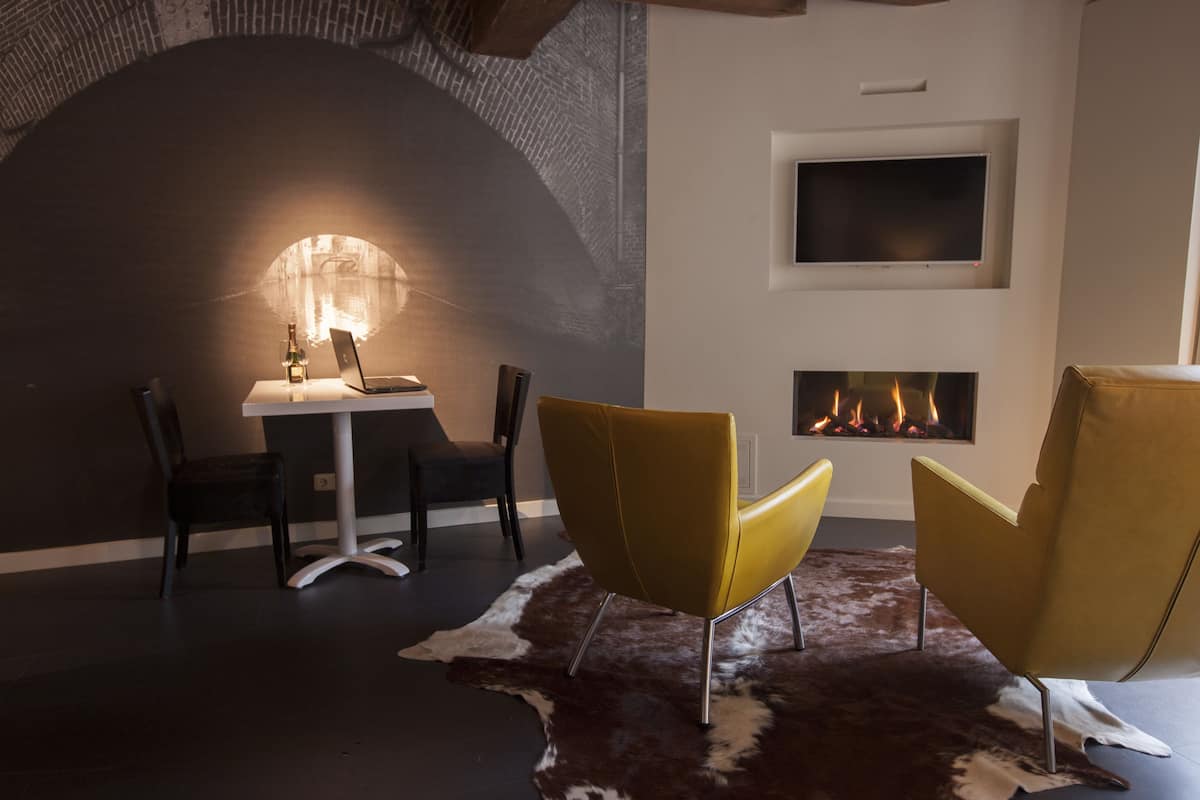 Un interior moderno con chimenea, una mesa de comedor con sillas y una computadora portátil sobre la mesa.
