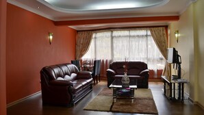 Una sala de estar con dos sofás de cuero, una mesa de centro y un televisor sobre un mueble.