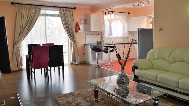 Una sala de estar moderna con una mesa de centro de vidrio, un sofá y un comedor con sillas.