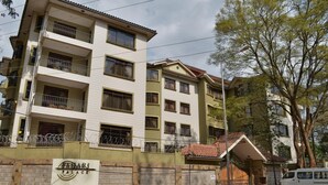 Un edificio de varios pisos con balcones, un letrero que dice "FAMARI PALACE" y una entrada con portones.