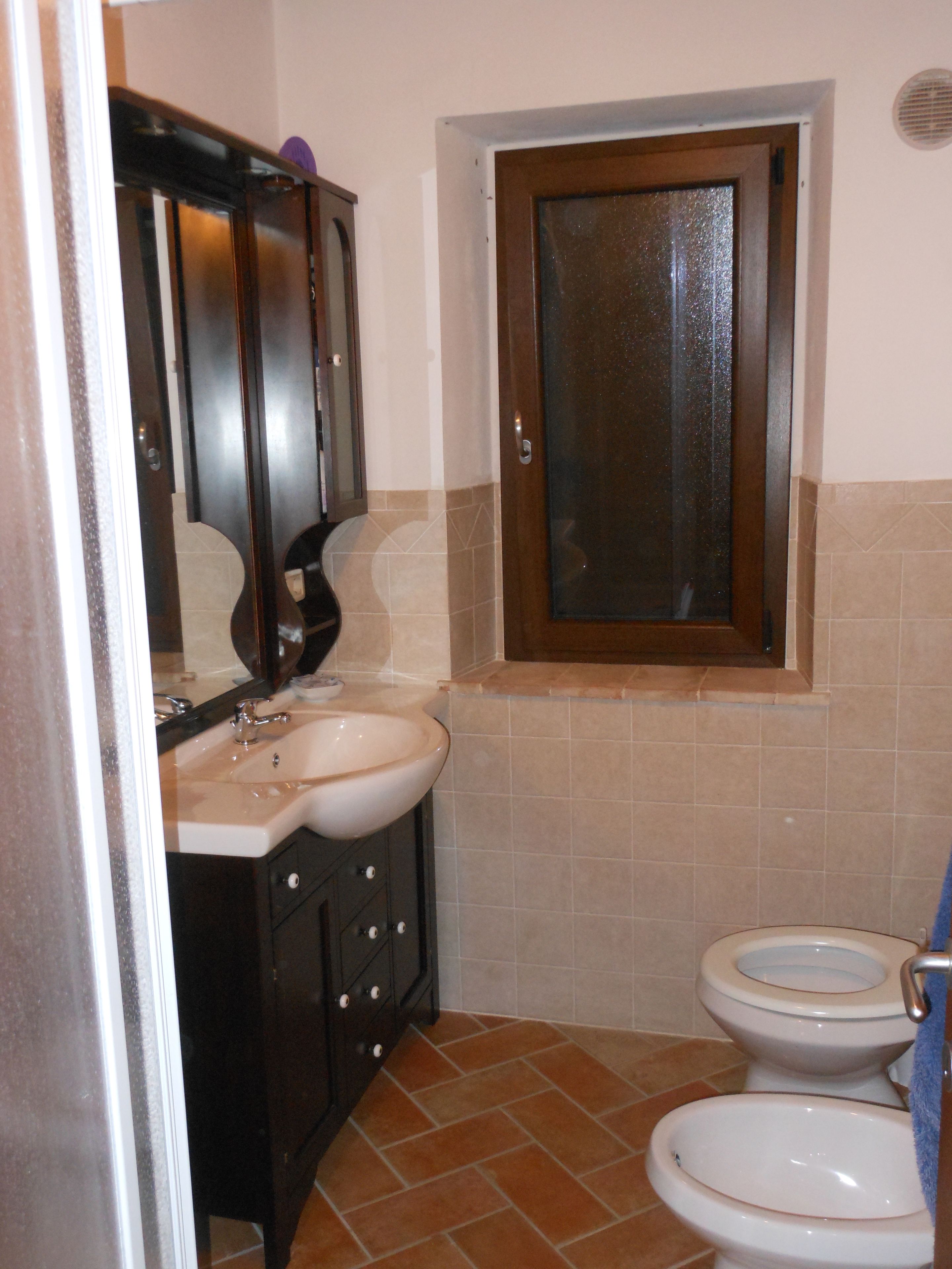 A small bathroom with a sink, mirror, and two toilets.