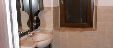 A small bathroom with a sink, mirror, and two toilets.