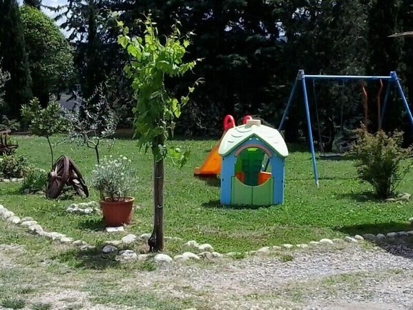 A children's play area with a slide, a swing set, and a small house-like structure.