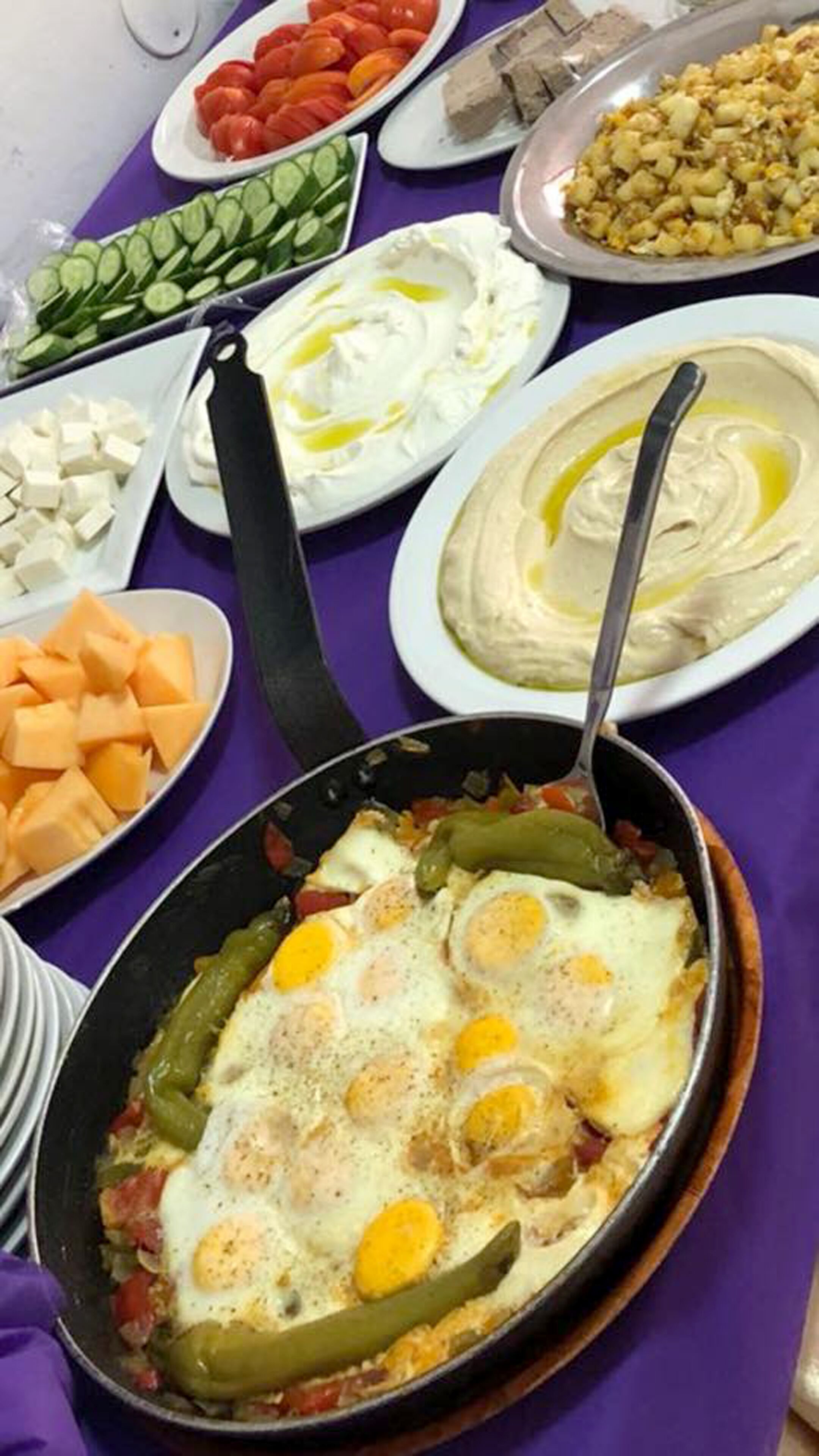 Una varietà di piatti con uova, verdure e salse su un tavolo.