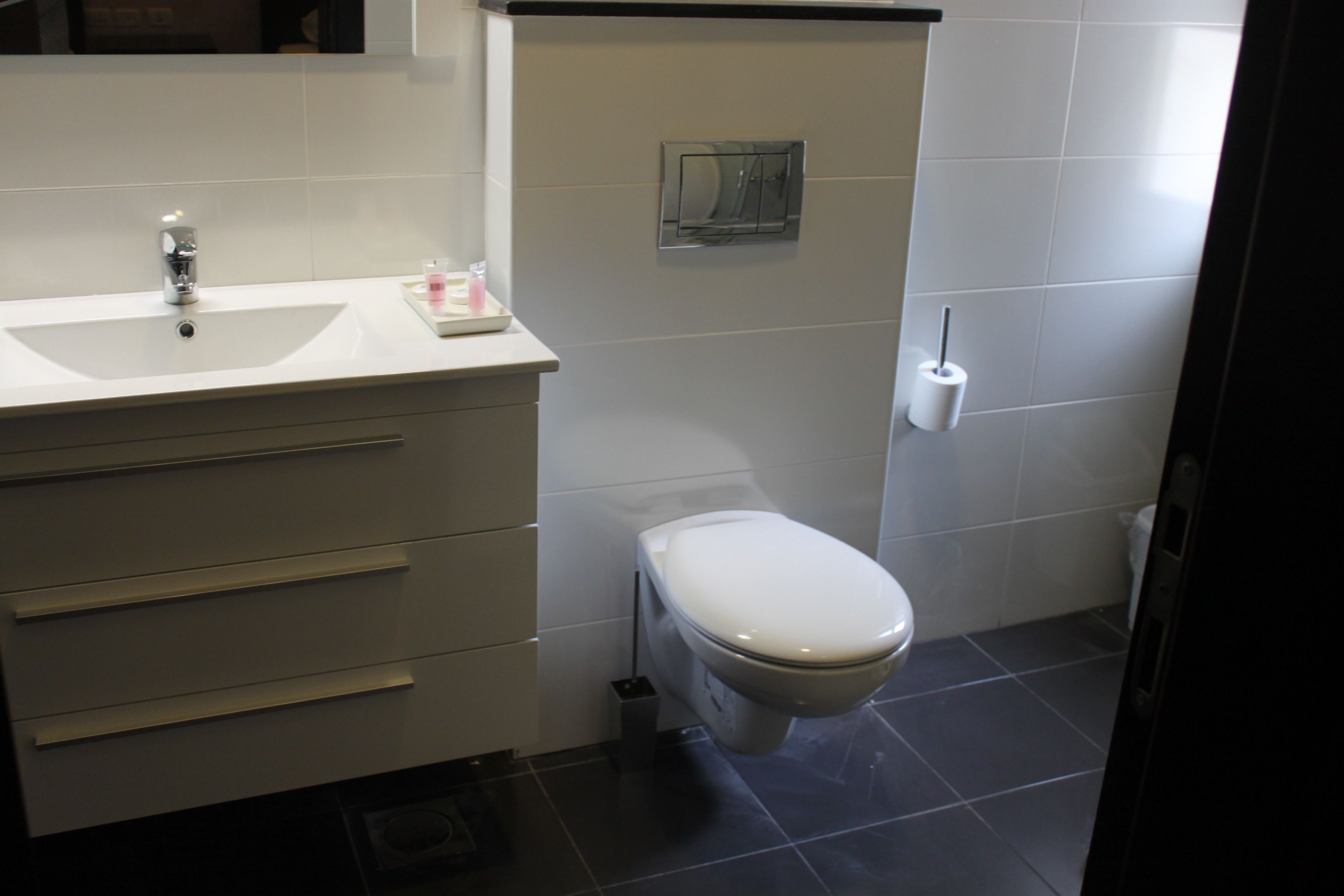 Een badkamer met een wit wastafel, toilet en een klein spiegel.