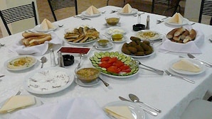 Une table dressée pour un repas, avec différents plats, notamment du pain, des légumes et une sauce rouge.