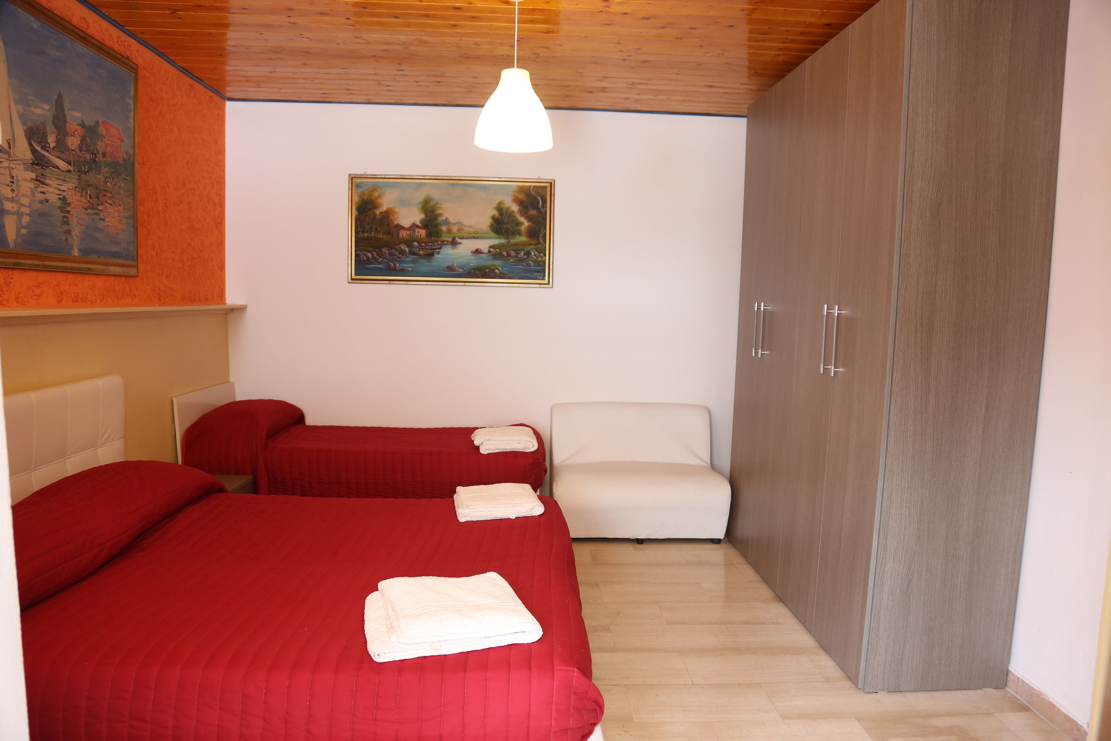 Un dormitorio con dos camas, una silla blanca, un armario y un cuadro en la pared.