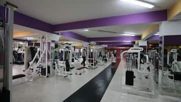 Una palestra con diverse macchine per esercizi, un percorso pedonale centrale e pareti viola.