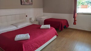 Ein Hotelzimmer mit zwei Betten, einem Bild an der Wand und einem Fenster mit Vorhängen.
