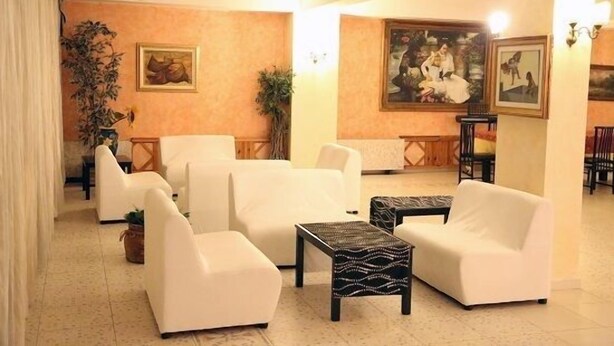 Eine geräumige Lobby mit weißen Sofas, einem Couchtisch, einem Bild an der Wand und einer Pflanze.