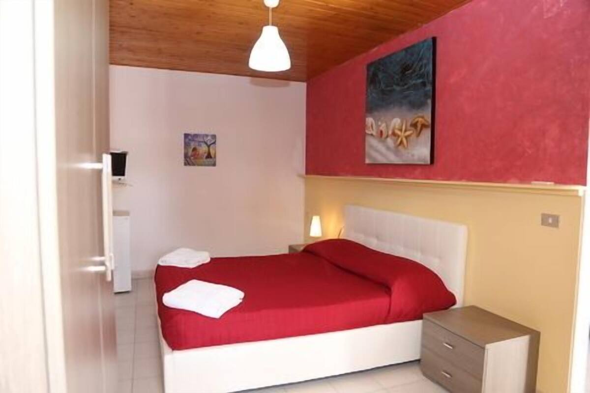 Ein Schlafzimmer mit Bett, Nachttisch, Lampe und einem Bild an der Wand.