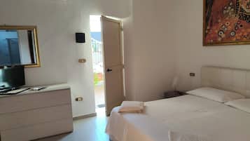 Ein Hotelzimmer mit einem Bett, einem Schminktisch, einem Fernseher und einem Bild an der Wand.