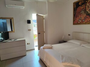 Ein Hotelzimmer mit einem Bett, einem Schminktisch, einem Fernseher und einem Bild an der Wand.