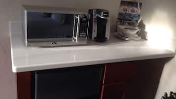 Une petite cuisine équipée d’un four à micro-ondes, d’une machine à café et d’un petit réfrigérateur.