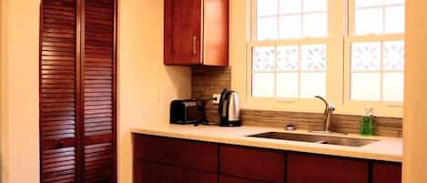 Una cocina con armarios de madera, una encimera, un fregadero y un ventanal con detalles decorativos.