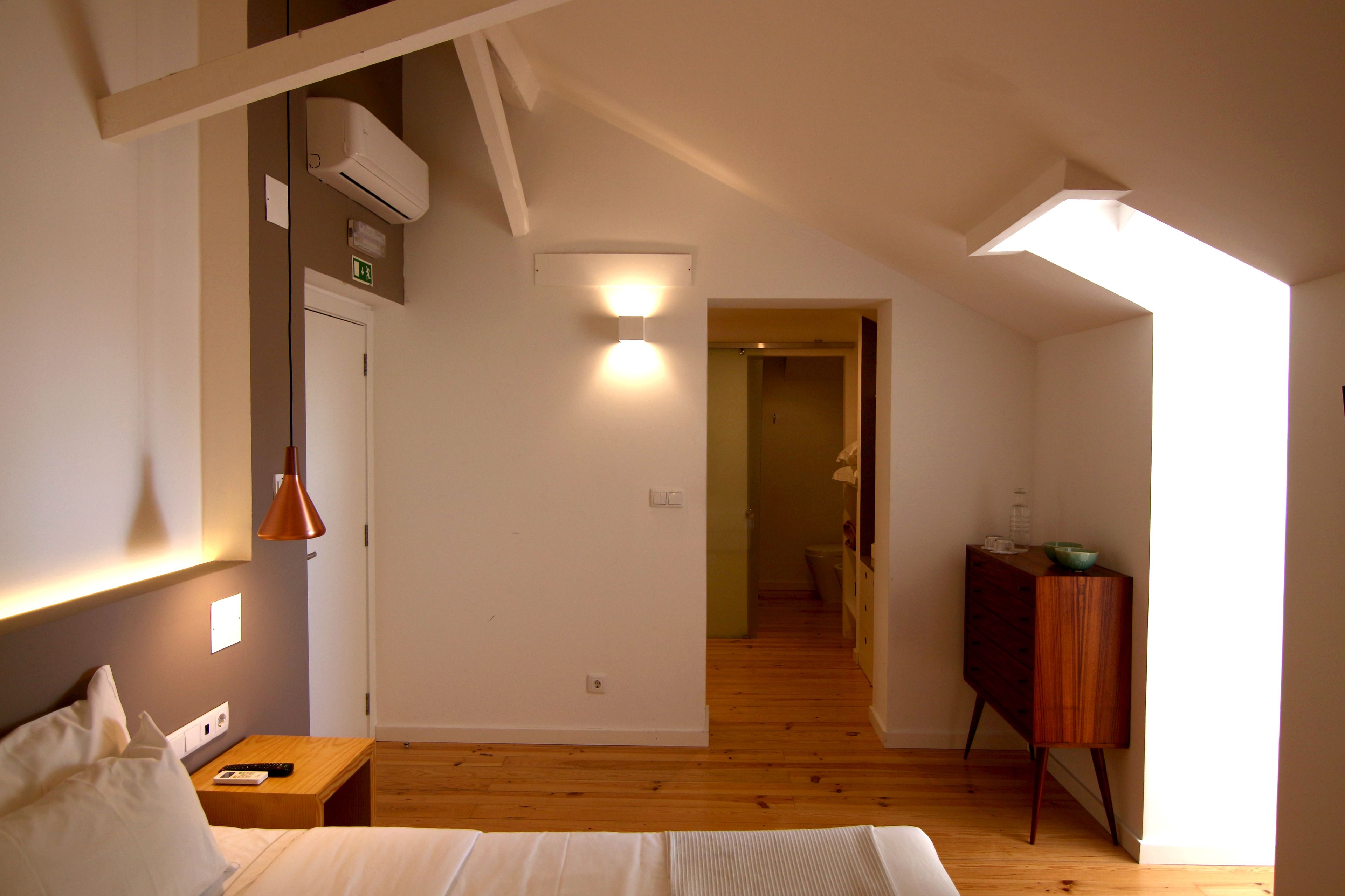 Une chambre à coucher comprenant un lit, une table de chevet, une lampe et un appareil de climatisation.