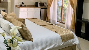 A hotel room with a large bed, a small kitchenette, and a TV. - Inn Galerias Hotel (Aguascalientes)