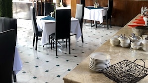 A restaurant with tables set for dining, a bar area, and a buffet setup. - Inn Galerias Hotel (Aguascalientes)