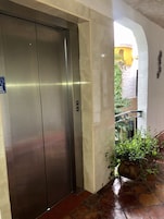 Un ascensor en un edificio con piso de baldosas y una planta cerca de la entrada.