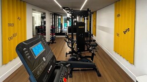 A gym with exercise equipment, wooden floors, and yellow walls. - Uniclass Hotel Lapa (São Paulo)